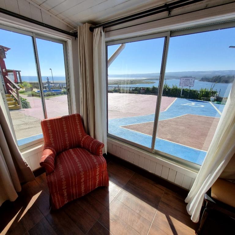 sala de estar con silla y ventana grande en Max & Mar Pichilemu, en Pichilemu
