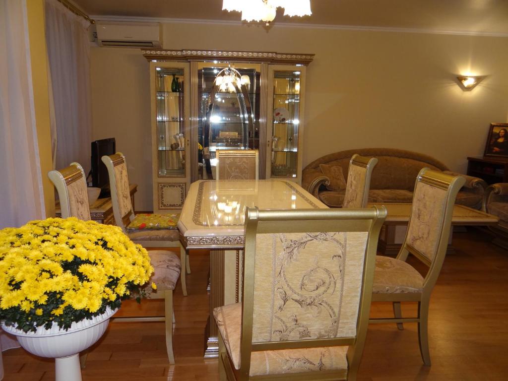 ein Esszimmer mit einem Tisch, Stühlen und gelben Blumen in der Unterkunft Luxury Versailles Apartments Center Opera in Burgas City