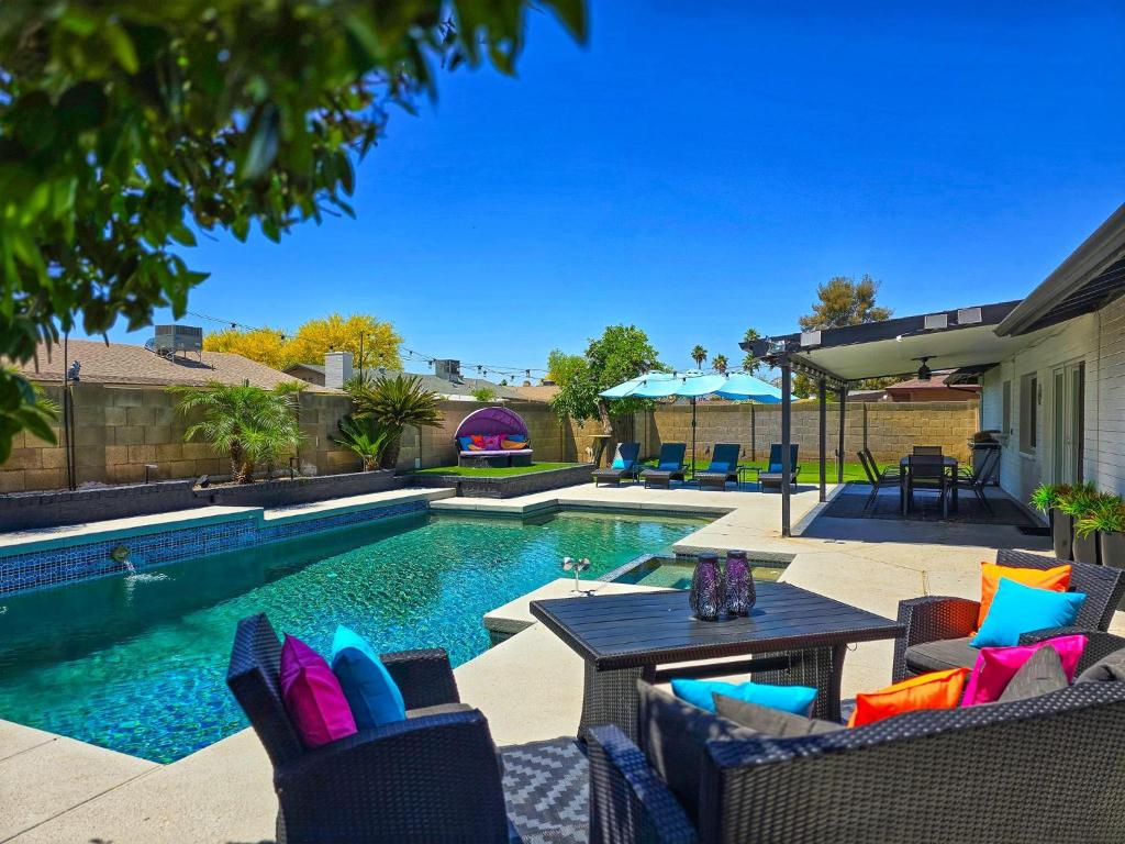 um quintal com uma piscina com cadeiras e uma mesa em Lazy Palms em Tempe