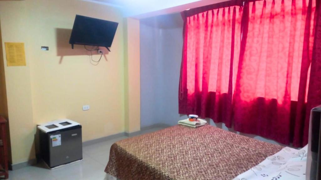 ein Schlafzimmer mit einem Bett und einem roten Vorhang in der Unterkunft Hospedaje Roma in Huánuco