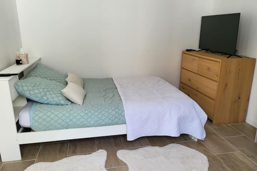 a bedroom with a bed and a dresser with a television at 2 pièces d'environ 25m2 in Torcy