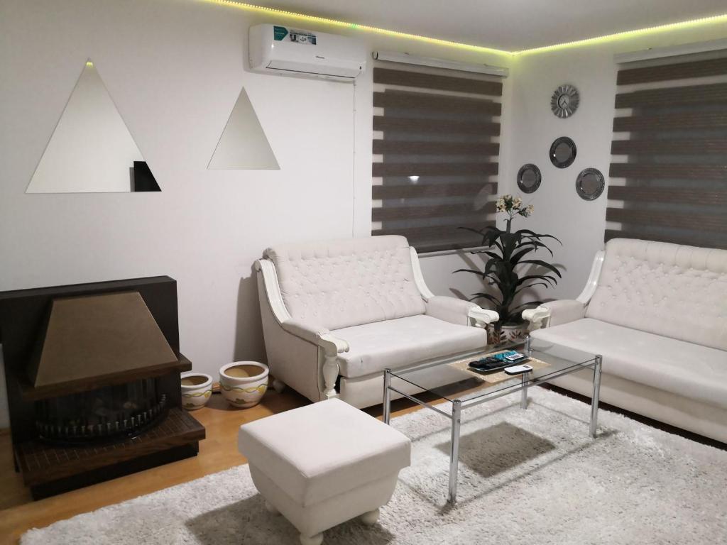 a living room with two white chairs and a fireplace at Apartment Mirror in Visoko