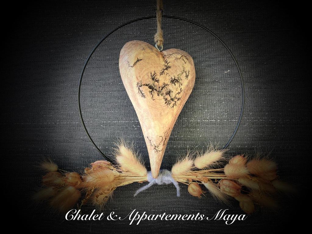 un corazón de madera colgando de una rejilla con plumas en Chalet Maya, en Schladming