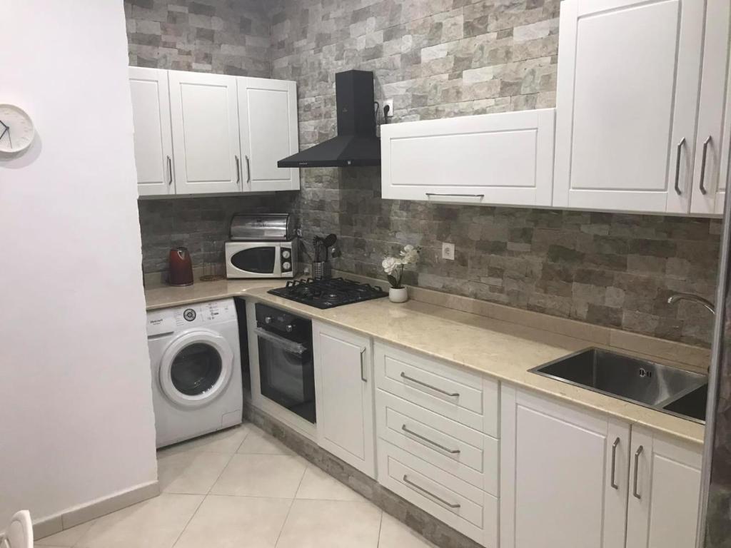 a kitchen with white cabinets and a washer and dryer at Bel appartement Ghazaouet vue sur mer in Ghazaouet