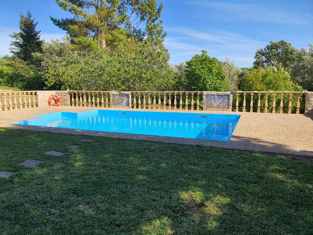 a blue swimming pool in a yard next to a fence at Casa do Lago - Villas de Campo in Ferreira do Zêzere