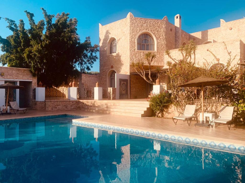 a villa with a swimming pool in front of a house at Le Domaine d'Eden - Villa luxueuse, piscine, spa et personnel in Essaouira