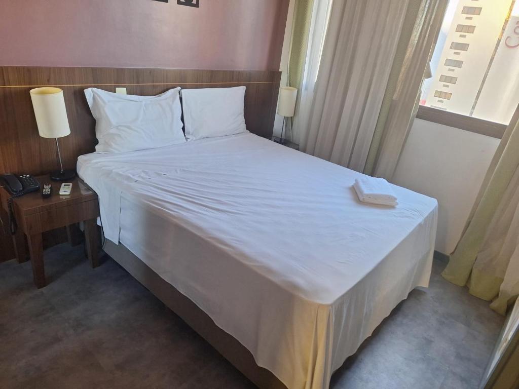 Hóspede já Nobile suites في برازيليا: غرفة نوم بسرير كبير عليها شراشف ووسائد بيضاء