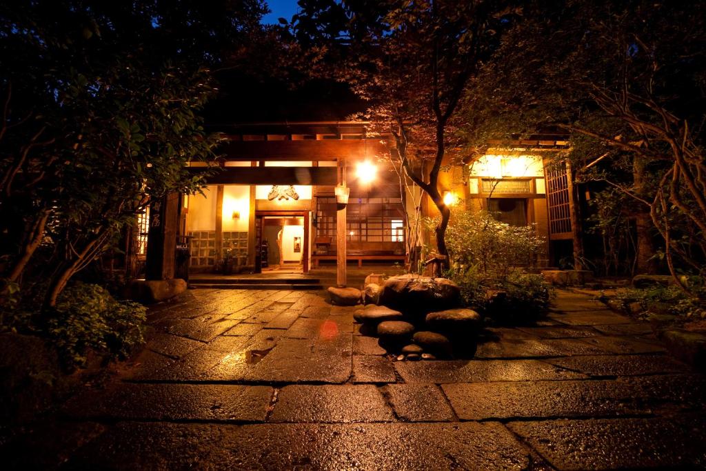 una pasarela de piedra frente a un edificio por la noche en Hatago Kayausagi en Hita