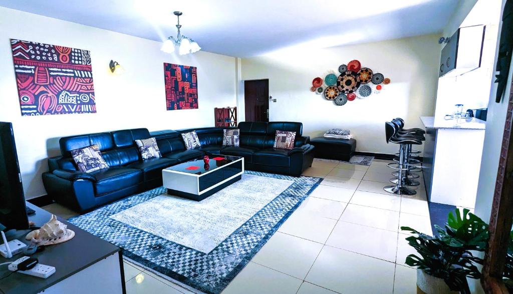 een woonkamer met een zwarte bank en een tafel bij Tribal Themed 3BR Penthouse in Nairobi