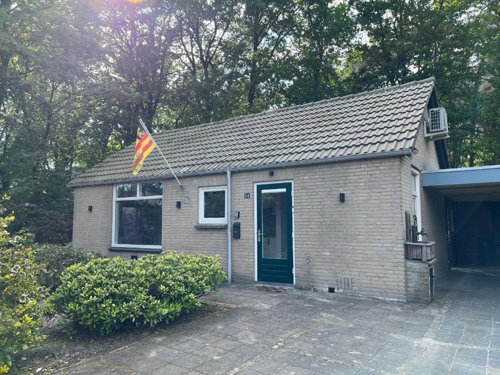 una pequeña casa con una bandera delante de ella en Boshuis Luyksgestel 2-6 personen, veel privacy!, en Luyksgestel