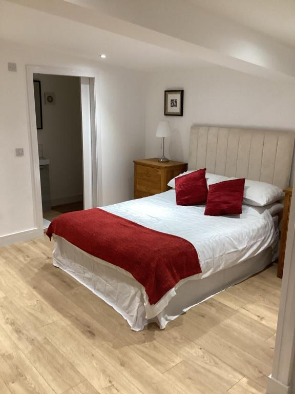 een slaapkamer met een groot bed met rode kussens bij The Tack Shed in Dairsie
