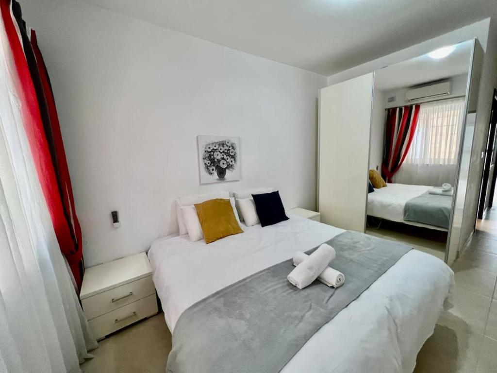a bedroom with a large white bed and a mirror at Blossom bliss in Marsaskala