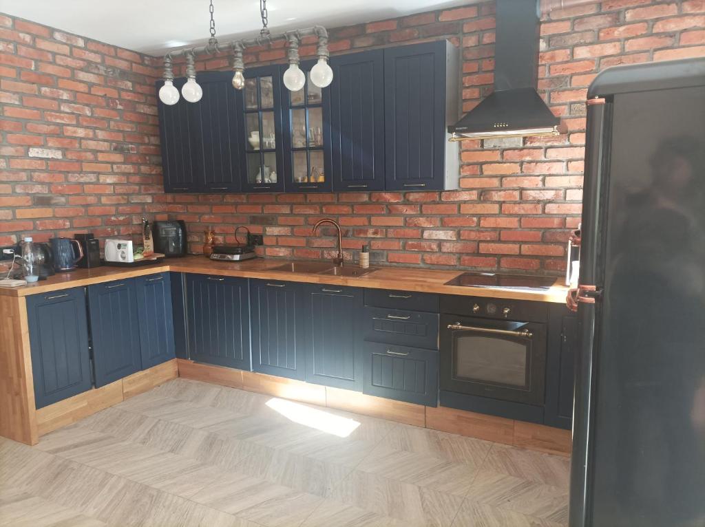 a kitchen with blue cabinets and a brick wall at Dom Gdansk Przymorze 7 pokoi mini SPA in Gdańsk