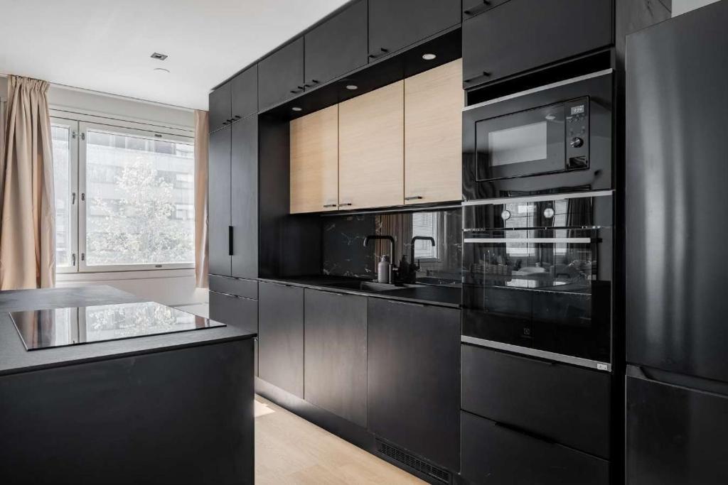 a kitchen with black cabinets and a black refrigerator at Lux Eight, 2-Bedroom City Centrum in Turku