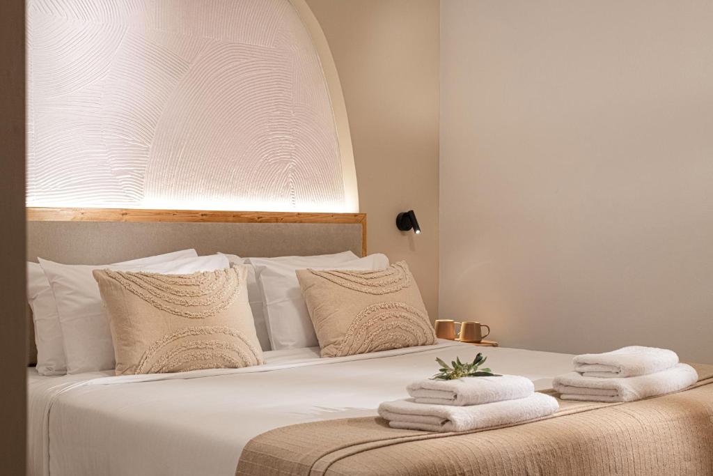 een slaapkamer met een wit bed en handdoeken bij Elea Suites & Residences in Gouves