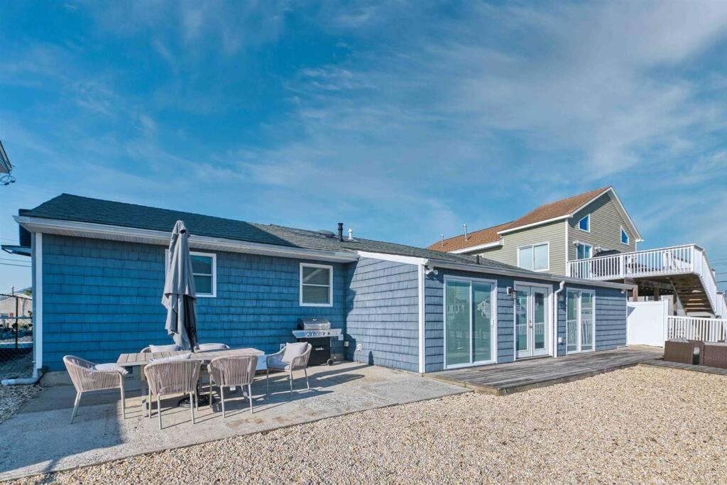 ein Haus mit einer Terrasse mit einem Tisch und einem Sonnenschirm in der Unterkunft Mystic Island waterfront oasis in Little Egg Harbor Township