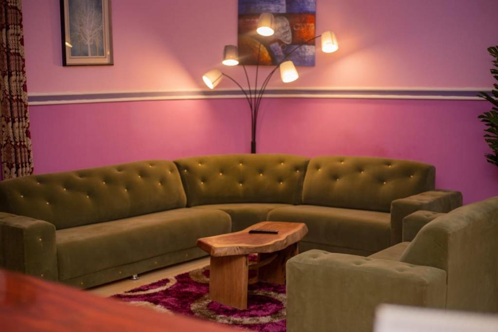 a living room with a green couch and a table at Dominion Embassy Lodge in Sekondi-Takoradi