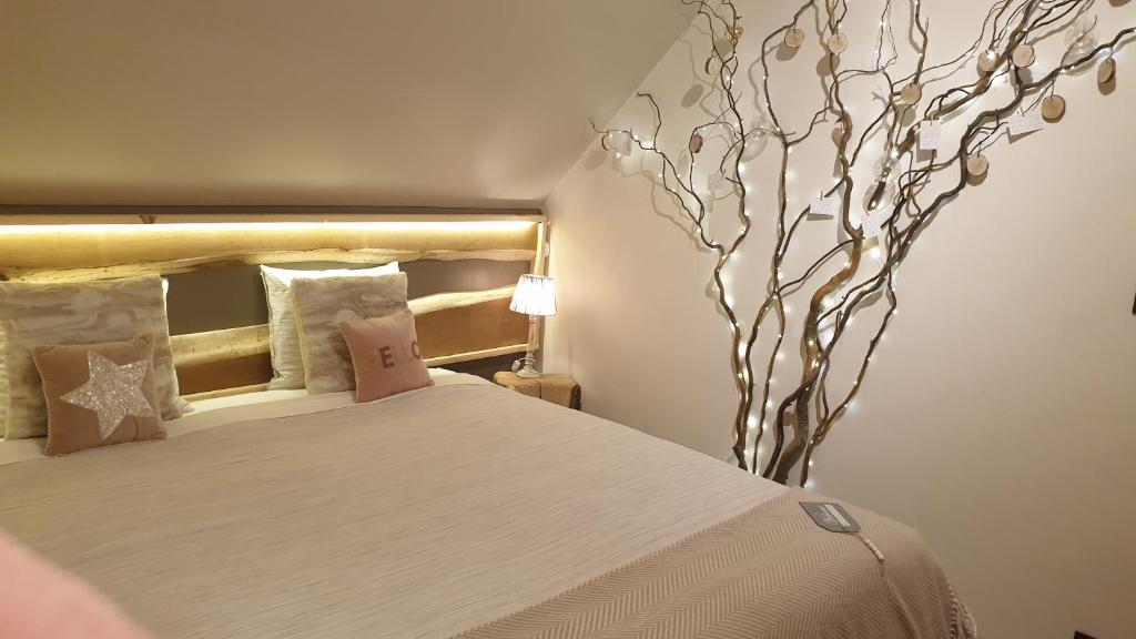 una camera da letto con un grande letto con un albero sul muro di Chambre d'hôte Saint-Symphorien Mons a Mons