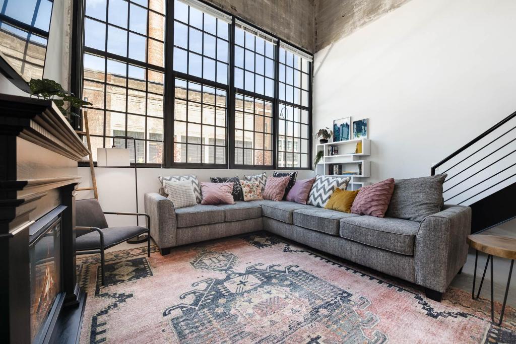 MainevilleにあるNew Industrial Loft Space on River and Bike Trailのソファと窓のあるリビングルーム