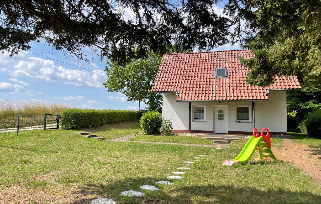 a small house with a green yard with a slide at Awesome Home In Angermnde-herzsprung With Kitchen in Herzsprung