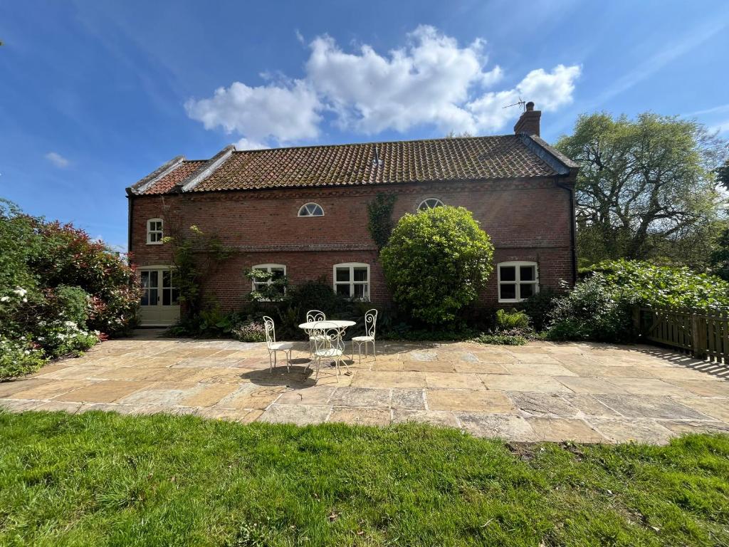 a brick house with a table and chairs in front of it at The Old Barn in Market Rasen