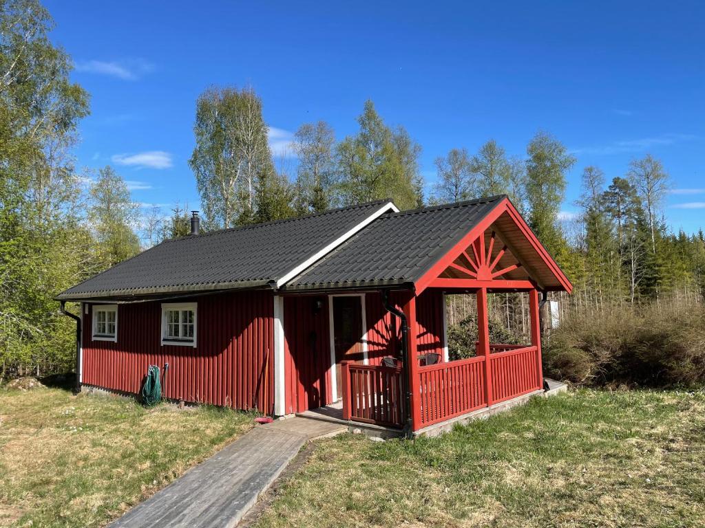 una cabina roja con techo negro en un campo en Björkebostugan at the end of the road, en Torsby