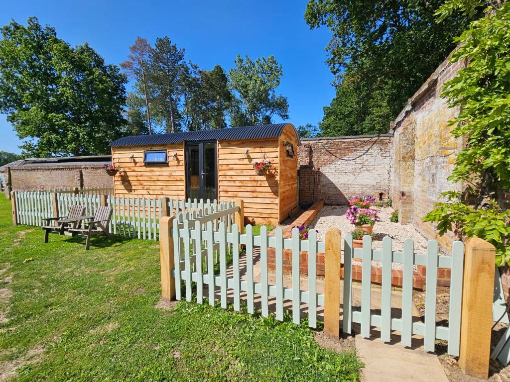 een houten huisje in een tuin met een hek bij Gatwick Hideaway Hut in Charlwood