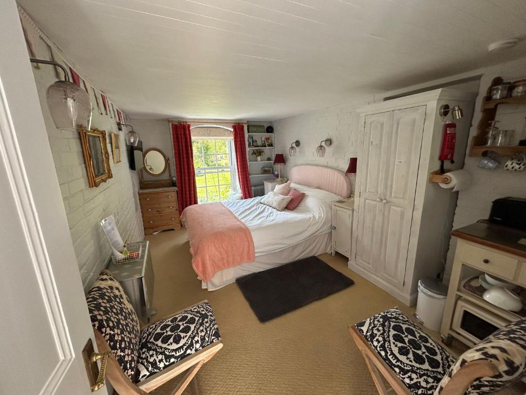 een kleine kamer met een bed en stoelen erin bij Cosy Cottage ground floor bedroom ensuite with private entrance in Chichester