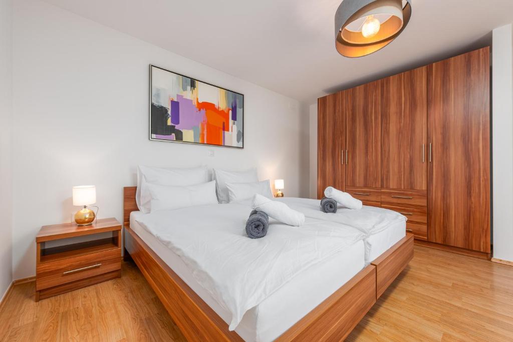 um quarto com uma grande cama branca e armários de madeira em Apartments L&D em Biograd na Moru