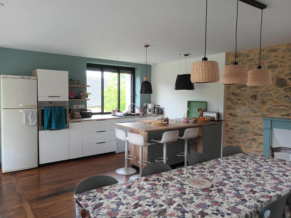 une cuisine avec des armoires blanches et une table avec des chaises dans l'établissement La maison de Théophile, à La Bastide-lʼÉvêque