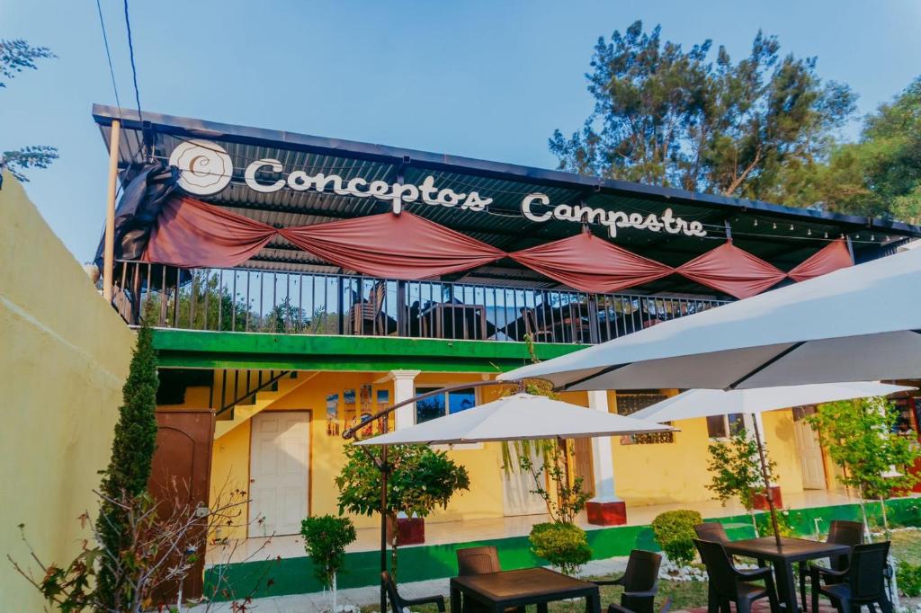 a cafe with tables and umbrellas in front of a building at Conceptos Campestre in Huehuetenango