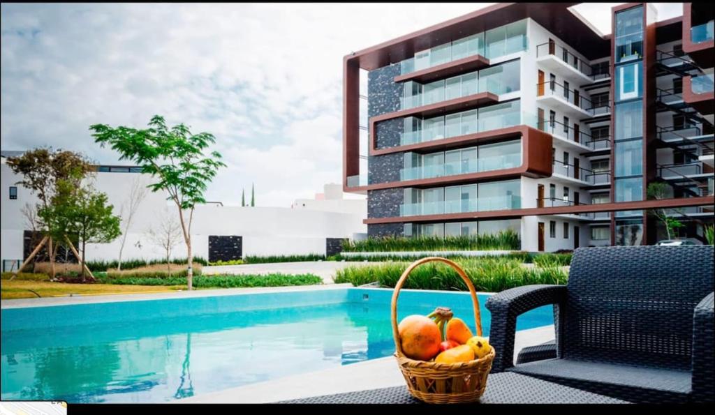 a basket of fruit sitting next to a swimming pool at MS Excelente Suite Alberca Milenio C32 in Querétaro