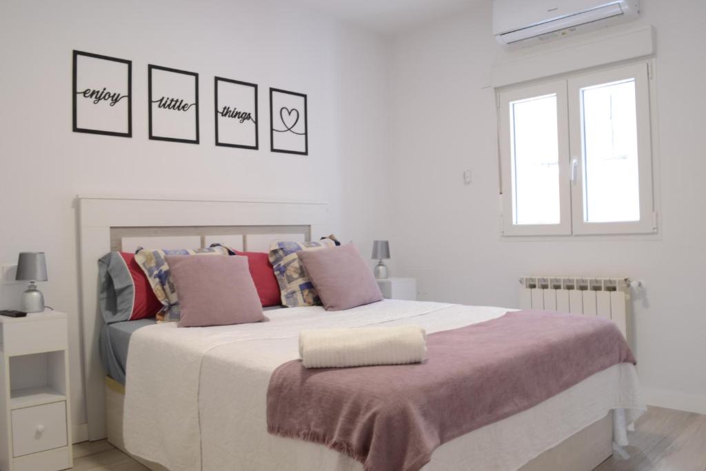 a white bedroom with a large bed with pink pillows at Bonito Apartamento Madrid Rio in Madrid