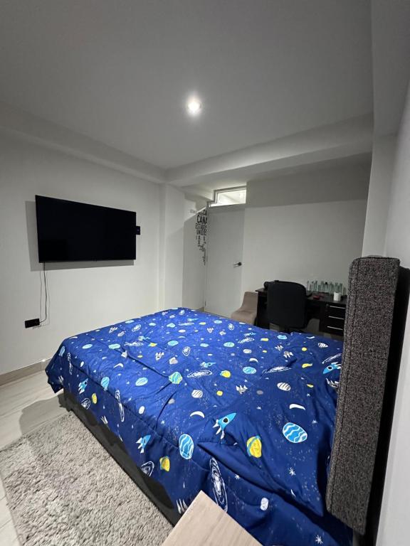 1 dormitorio con 1 cama con edredón azul en Departamento Amoblado Vista Externa, en Huánuco