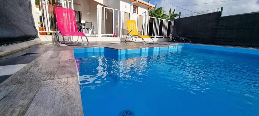 a swimming pool with chairs next to a house at Lacazavanoo in Baillif