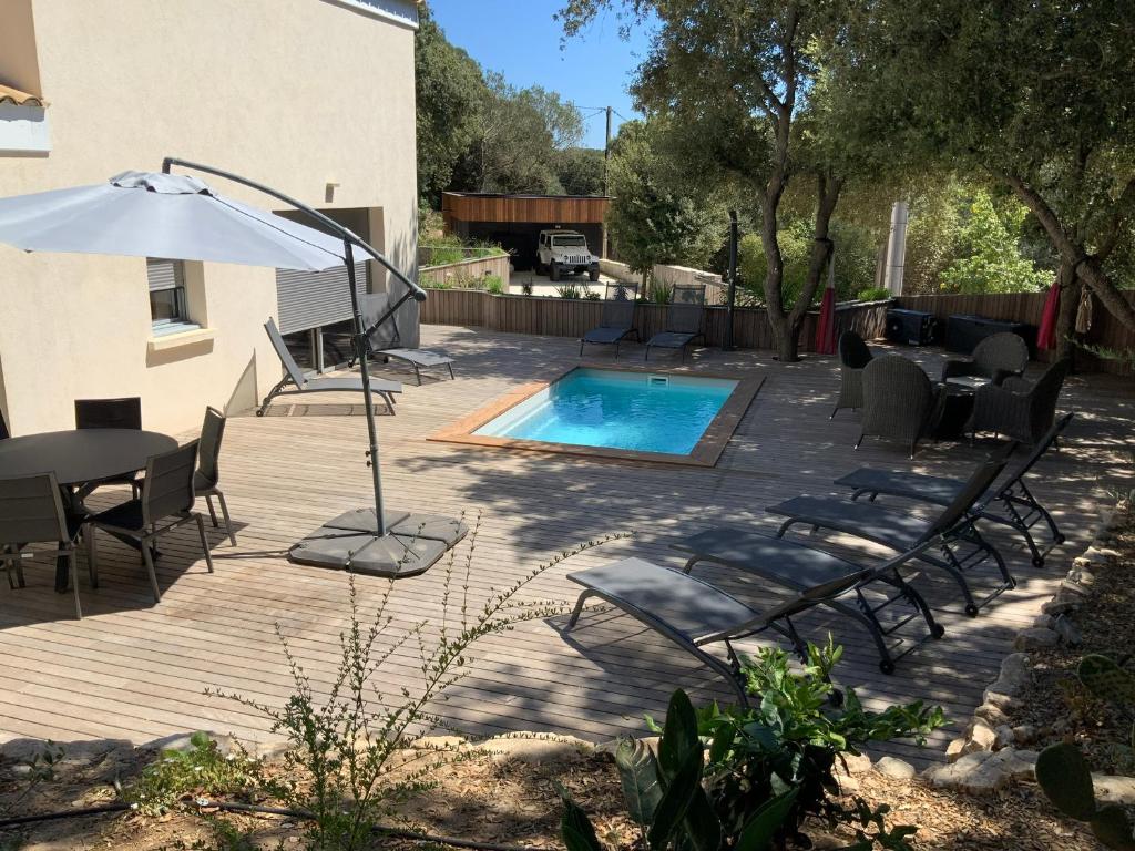 a patio with a pool and chairs and an umbrella at Villa STEVAN in Bonifacio