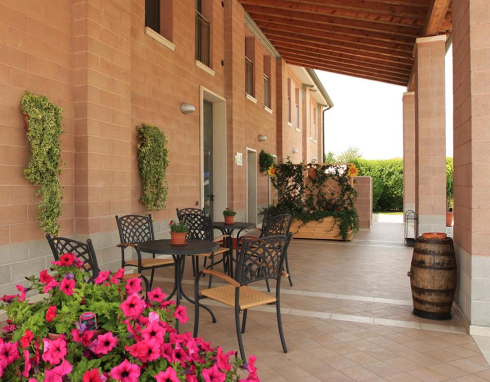 un patio con mesas, sillas y flores rosas en Agriturismo B&B Il Girasole, en Oriago Di Mira