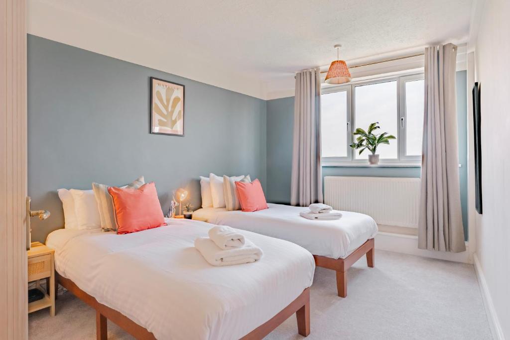 twee bedden in een kamer met blauwe muren en ramen bij Charming LDN apt with free parking in Londen