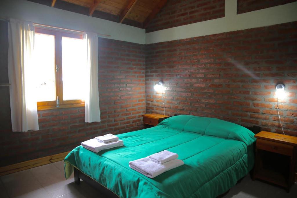 ラゴ・プエロにあるChacra confluenzaのレンガの壁、緑のベッドが備わるベッドルーム1室が備わります。