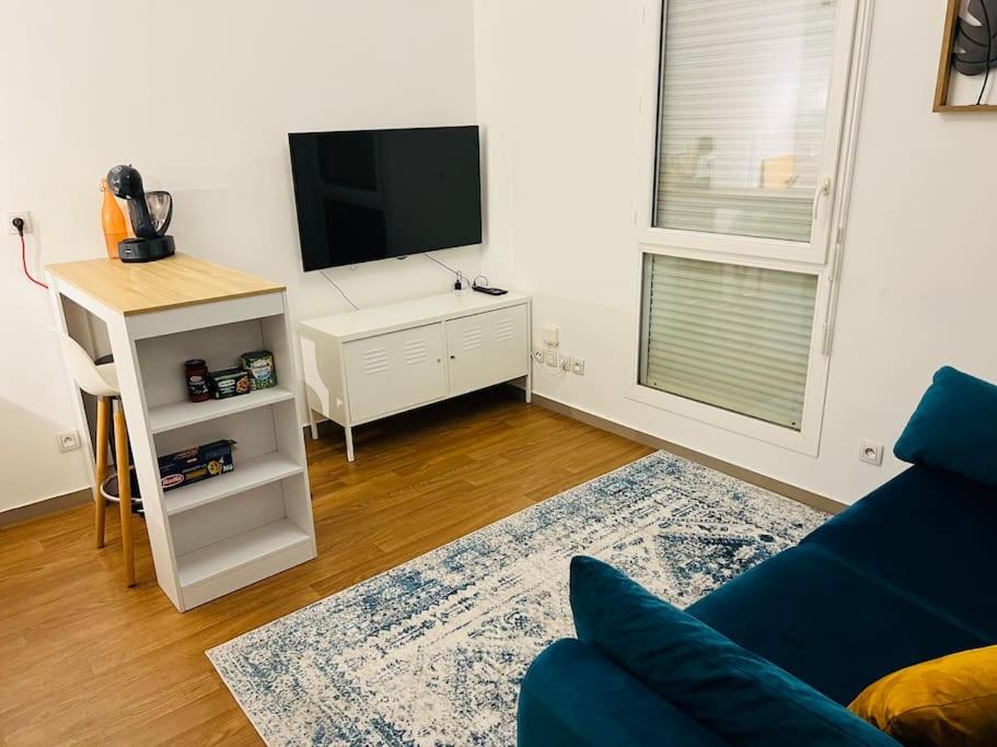 - un salon avec une télévision et un canapé bleu dans l'établissement Studio proche Part-Dieu, à Villeurbanne
