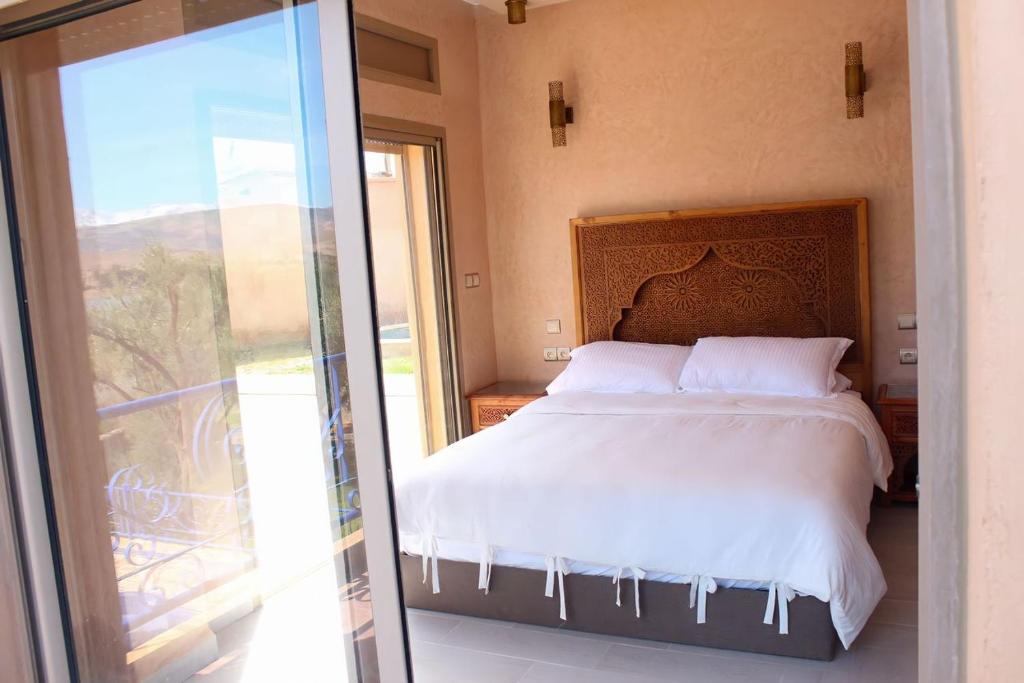 a bedroom with a bed and a sliding glass door at Villa Piscine Privée Jaccuzi in Lalla Takerkoust