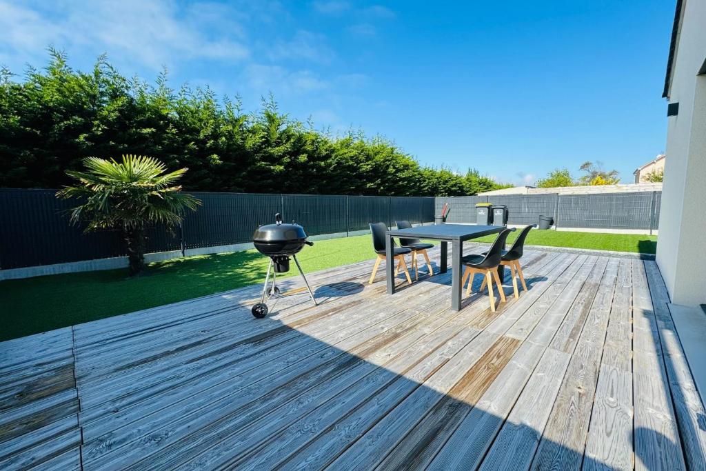 een grill en een tafel en stoelen op een terras bij Splendid new house in Ouistreham in Ouistreham
