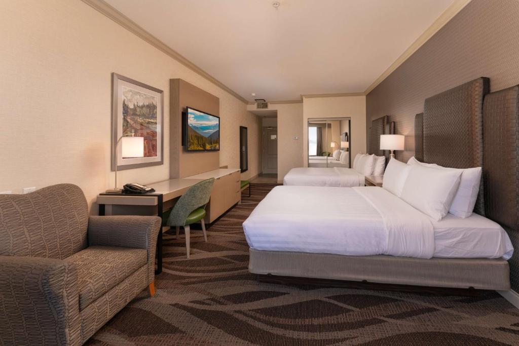 a hotel room with two beds and a couch and a desk at Prestige Harbourfront Resort, WorldHotels Luxury in Salmon Arm
