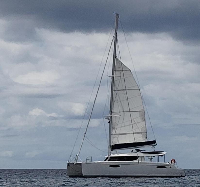 a sailboat in the ocean on a cloudy day at Catamaran baie des 3 ilets in Les Trois-Îlets