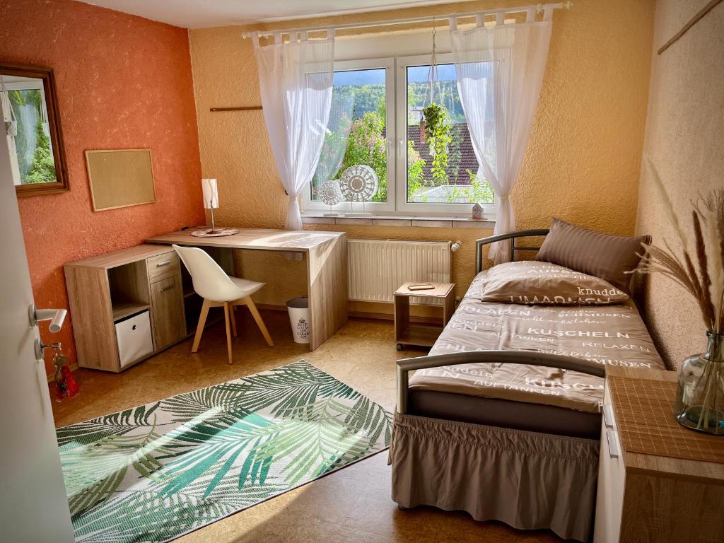 Schlafzimmer mit einem Bett, einem Schreibtisch und einem Fenster in der Unterkunft neXt doOr Donau Gästezimmer und Suite in Wurmlingen