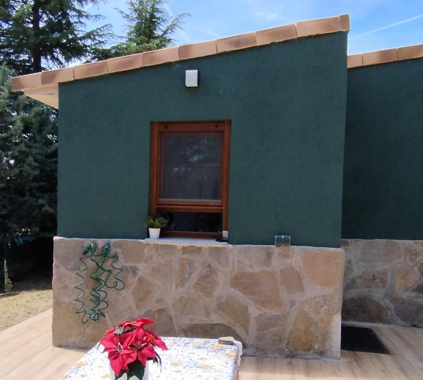 una casa verde con banco y ventana en MONTESCLAROS Apartamento de 2 dormitorios, en Cerceda