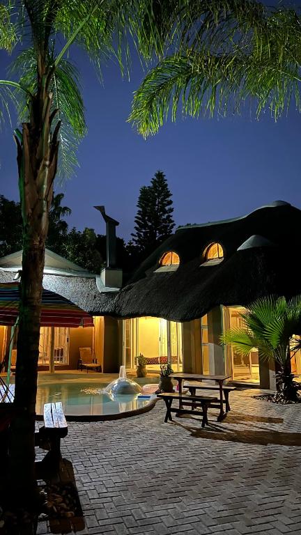 a building with a pool with a table and a palm tree at STAY In TEHAMA in Cape Town