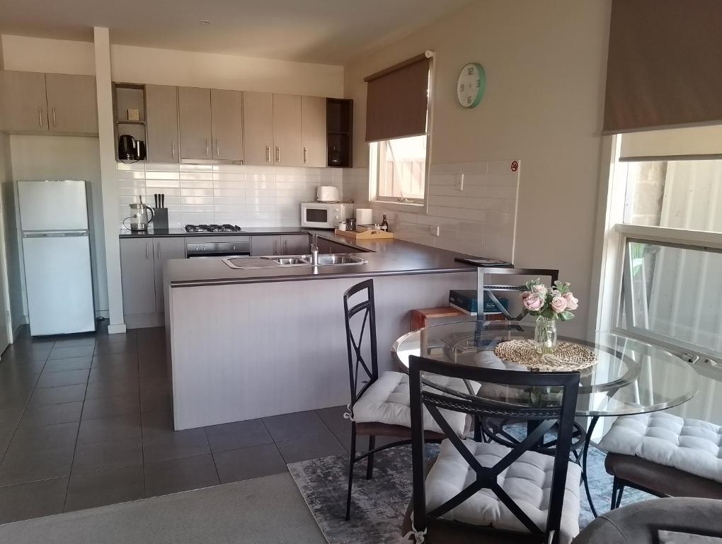 a kitchen with a table and a kitchen with a refrigerator at Lovely 2 bedroom apartment across from Shepp Lake. in Shepparton