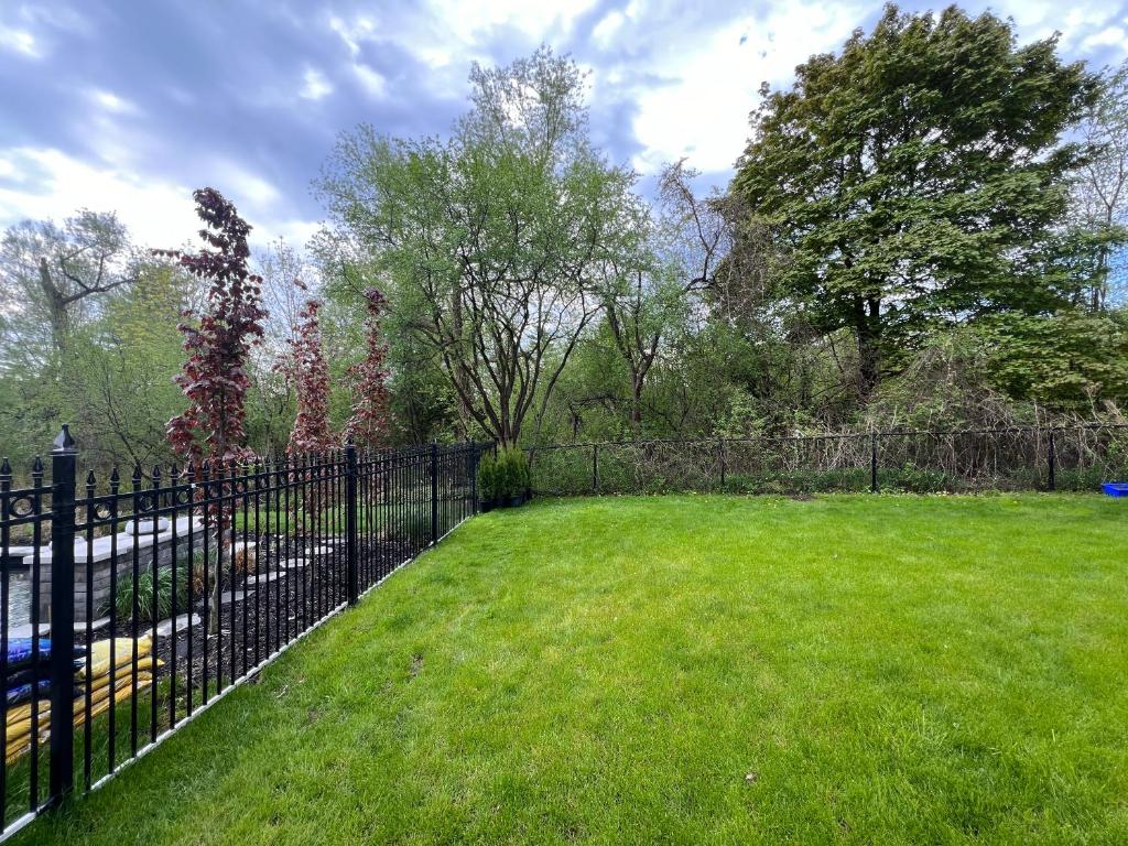 uma cerca preta num quintal com um campo verde em Cozy, brand-new, 2BDR,walkout apt, free parking em Richmond Hill