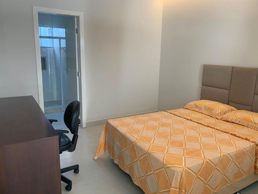 een slaapkamer met een bed, een bureau en een stoel bij Suíte completa próximo a Capitólio e Canastra in Piuí